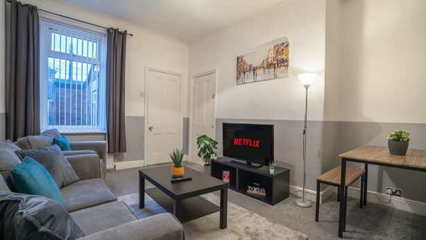 Ett modernt vardagsrum med en soffa, ett soffbord, en tv och en tavla på väggen.