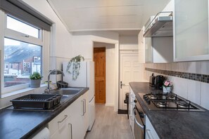 A modern kitchen with a gas stove, a sink, and a window overlooking a cityscape. - 3BR Gateshead Stay-Parking-Nr Newcastle &Quayside (Tyne and Wear)