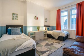 A bedroom with two beds, a desk, a radiator, and a window with curtains. - 3BR Gateshead Stay-Parking-Nr Newcastle &Quayside (Tyne and Wear)