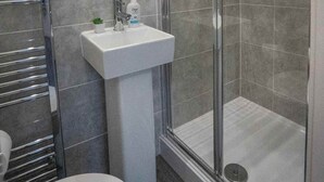 A bathroom with a glass-enclosed shower, a white sink, and a towel rack. - 10 Mins BAE Systems -Contractor Stay -Free Parking (Barrow-in-Furness)
