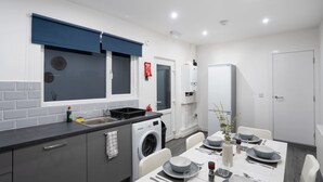 A modern kitchen with a washing machine, a sink, and a dining area with a table set for four. - 10 Mins BAE Systems -Contractor Stay -Free Parking (Barrow-in-Furness)