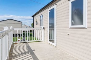 A single-story mobile home with a white exterior, a covered deck, and a sliding glass door. - Seton Sands 3BR Spacious Caravan near Edinburgh (Port Seton)