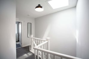 A staircase with white railings, a skylight, and a door leading to another room.