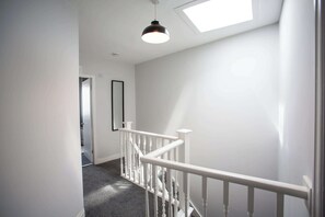 A staircase with white railings and a skylight above.