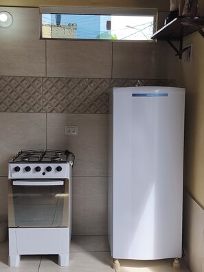 A kitchen with a gas stove, oven, and a white refrigerator. - Cozy Chalet, Your Beach Retreat (Cabo de Santo Agostinho)