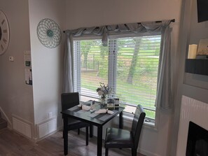 Un comedor con mesa, sillas, un adorno en la pared y una ventana con persianas.
