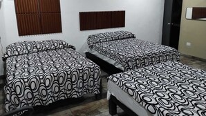Een kamer met twee bedden, een raam met zonwering, een kledingkast en een deur.
