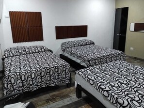 Ein Zimmer mit zwei Betten, einem Fenster mit Jalousien, einem Kleiderschrank und einer Tür.