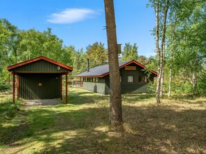 Zwei Hütten mit roten Dächern, einer Holzterrasse und blauem Himmel.