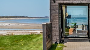 A modern building with a large glass door leading to a balcony overlooking a beach.