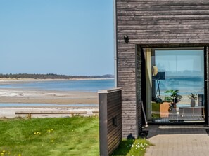 Ein modernes Gebäude mit einem großen Glasbalkon, der auf einen Strand blickt.