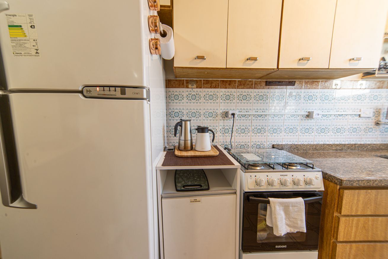 Una cocina compacta equipada con refrigerador, estufa, horno pequeño y microondas.