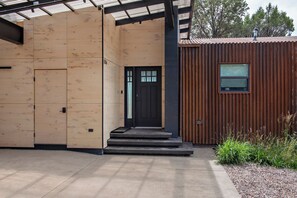 Un edificio con fachada de madera, una puerta negra y un ventanal pequeño.