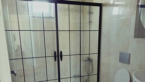 A bathroom with a glass shower enclosure, a toilet, and a vanity with a sink.
