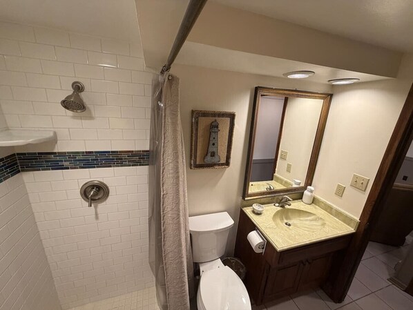 A bathroom with a shower, toilet, sink, and mirror. - Secluded A-Frame Lakefront with Sun Deck and Sauna (Lake Ozark)