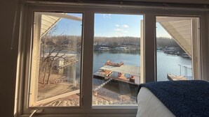 Een kamer met een groot raam met uitzicht op een steiger en het water.