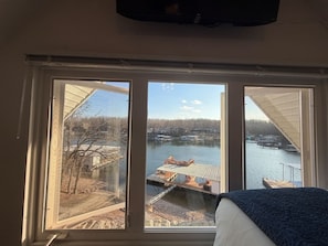 Een kamer met een groot raam met uitzicht op een steiger en het water.