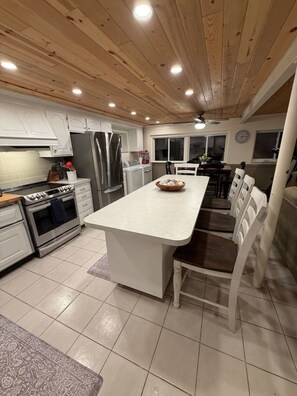 Una cocina moderna con armarios blancos, electrodomésticos de acero inoxidable y una isla central.