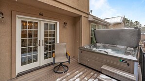 Un patio con un jacuzzi, una silla y un edificio con una puerta marcada '66'.