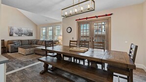 Un área de comedor con una amplia mesa de madera, un conjunto de sofás y una estantería.