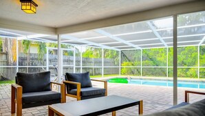 Un patio extérieur abrité, doté d’une piscine, d’un espace salon et de grandes fenêtres.