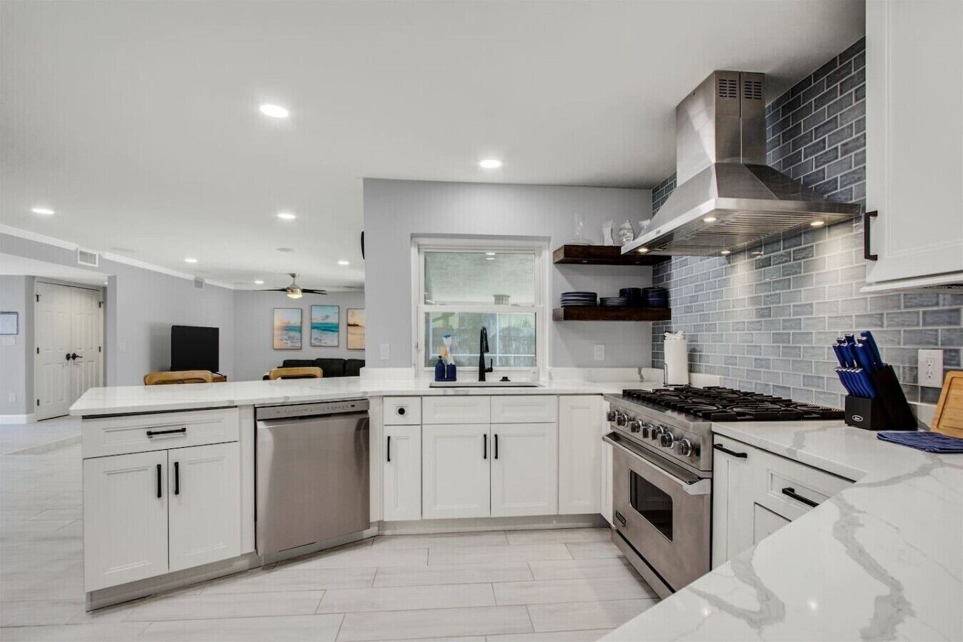 A modern kitchen with white cabinetry, a stainless steel range, and a brick backsplash.