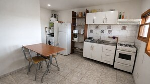 Eine kompakte Küche mit Esstisch, Waschmaschine, Kühlschrank, Herd und gefliestem Spritzschutz.