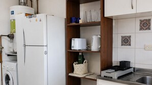 Eine kleine Küche mit Kühlschrank, Waschmaschine und Spüle.