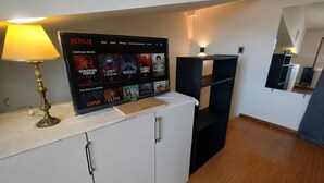 Ein Zimmer mit einem Netflix-Bildschirm, der verschiedene Sendungen zeigt, einer Lampe, einem Schrank und einem Spiegel.
