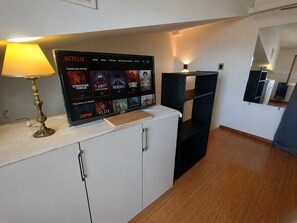 Ein Zimmer mit einem Netflix-Bildschirm, der verschiedene Sendungen zeigt, einer Lampe, einem Schrank und einem Spiegel.