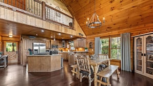 A spacious wooden cabin with a large dining area, a kitchen with modern appliances, and a balcony with a railing. - Sapphire Sky | Kids Fun Zone | Sauna | Mtn Views (Mineral Bluff)