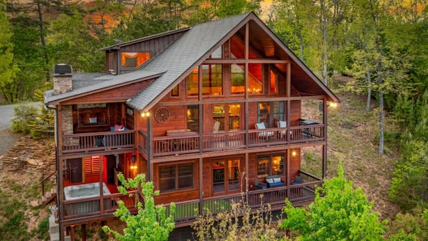 A multi-story log cabin with balconies, large windows, and a fireplace visible inside. - Sapphire Sky | Kids Fun Zone | Sauna | Mtn Views (Mineral Bluff)