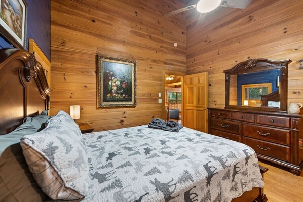 A wooden-paneled room with a bed, dresser, and a framed picture on the wall. - A Rustic Reprieve in Blue Ridge, Ga | Black Stag Lodge (Blue Ridge)