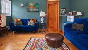 Ein Wohnzimmer mit zwei blauen Sofas, einem Couchtisch und einem farbenfrohen Teppich.