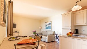 A compact living space with a dining area, a sofa, a kitchen with a coffee maker, and a TV mounted on the wall. - Provence Country Club by Interhome (L'isle sur la Sorgue)