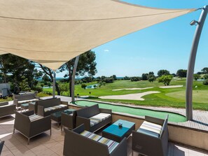 Uma área de estar externa com móveis de vime e vista para um campo de golfe.