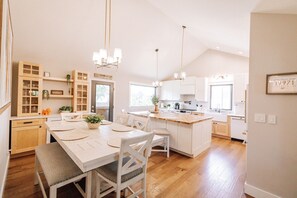 A modern kitchen with white cabinetry, a central island, and pendant lighting.