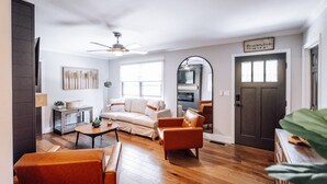 Ein Wohnzimmer mit einer Couch, Sesseln, einem Couchtisch und einem Kamin.