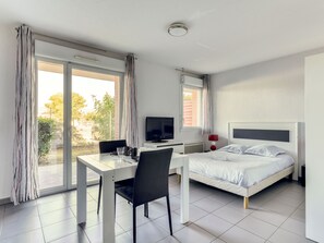 A hotel room with a bed, a desk with a chair, a television, and a window with curtains. - À proximité de la plage | Accès piscine | Parking (ARGELES-SUR-MER)