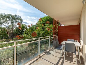 Ein Balkon mit Glasgeländer, einem Tisch und zwei Stühlen.