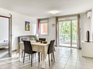 Un comedor con una mesa dispuesta para cuatro, sillas, una jofaina, cuencos y un reloj en la pared.