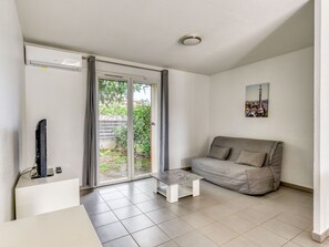 A living room with a grey sofa, a small coffee table, and a TV on a stand. - À 2 km de la plage | Piscine sur place | AC + Wifi (ARGELES-SUR-MER)