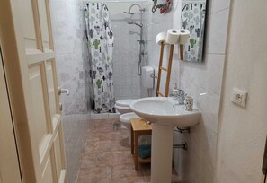 Ein Badezimmer mit Dusche, Toilette, Waschbecken und Spiegel.