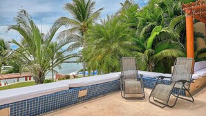 A poolside area with two lounge chairs, a tiled pool, and a view of the sea. - Beachfront Resort-Style Villa. Pickleball, tennis, Pools, Restaurant (Cruz de Huanacaxtle)