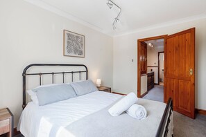 A neatly made bed with a headboard, a bedside lamp, and a towel on the bed.