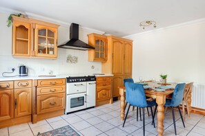 A kitchen with wooden cabinets, a stove, and a dining table with chairs.