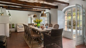 A dining area with a rustic wooden table, wicker chairs, and a view through an arched doorway. - Villa delle Silerchie 10, Emma Villas (Camaiore)