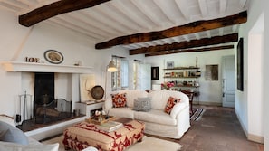 A cozy living room with a fireplace, a sofa, a coffee table, and a bookshelf. - Villa delle Silerchie 10, Emma Villas (Camaiore)