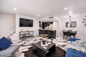 Ein modernes Wohnzimmer mit Flachbildfernseher, Couchtisch und Sofa.