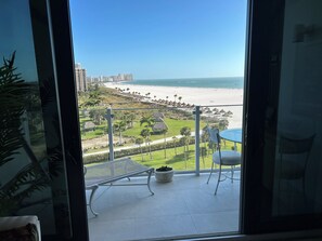 Ein Balkon mit Blick auf einen Strand, Palmen und eine Stadtlandschaft.